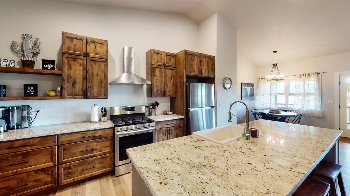 4592 A Awawa Road Hanapepe, HI 96705 - Photo 4 of 24 a kitchen with stainless steel appliances kitchen island granite countertop a refrigerator a stove a sink dishwasher and white cabinets with wooden floor