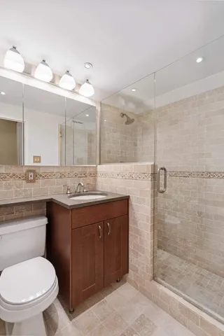 a bathroom with a granite countertop sink toilet a mirror and shower