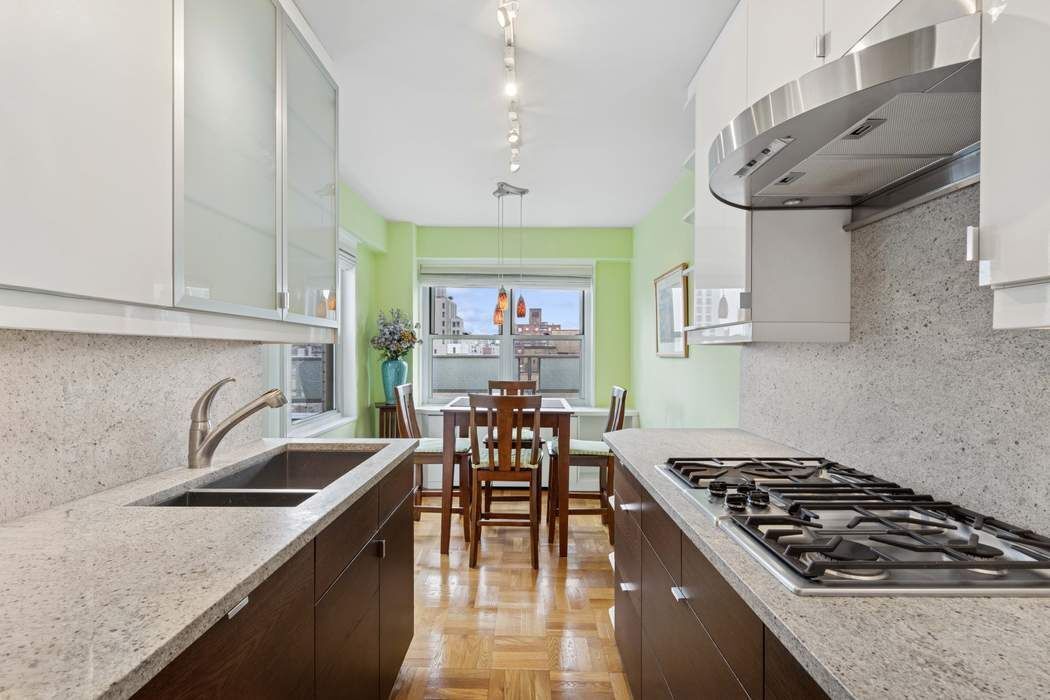 301 East 75th Street, Unit 19B Manhattan, NY 10021 - Photo 5 of 21 a kitchen with a stove a sink a dining table and chairs