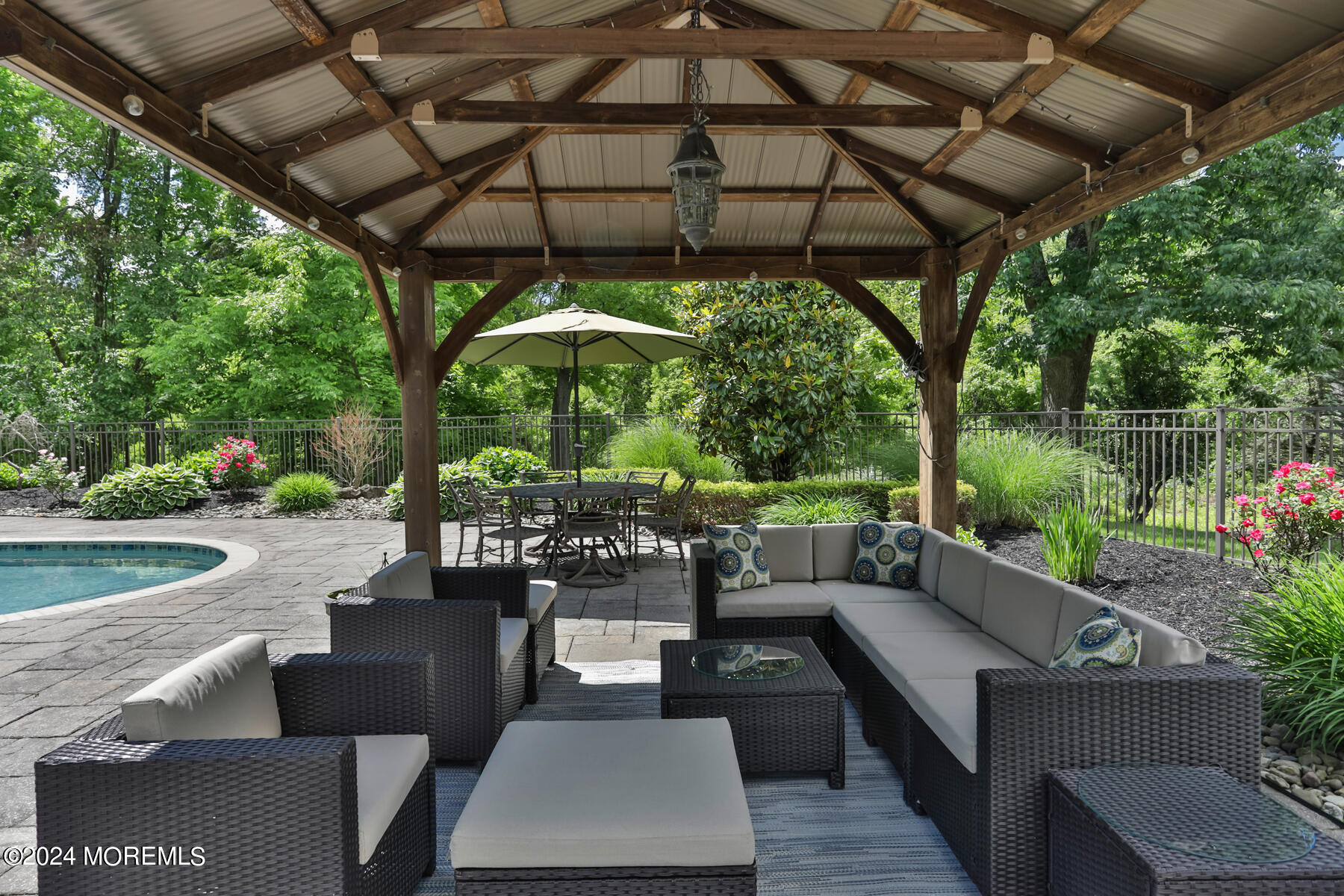 44 Meadowview Drive Colts Neck, NJ 07722 - Photo 49 of 68 a view of a patio with couches table and chairs under an umbrella with a small yard