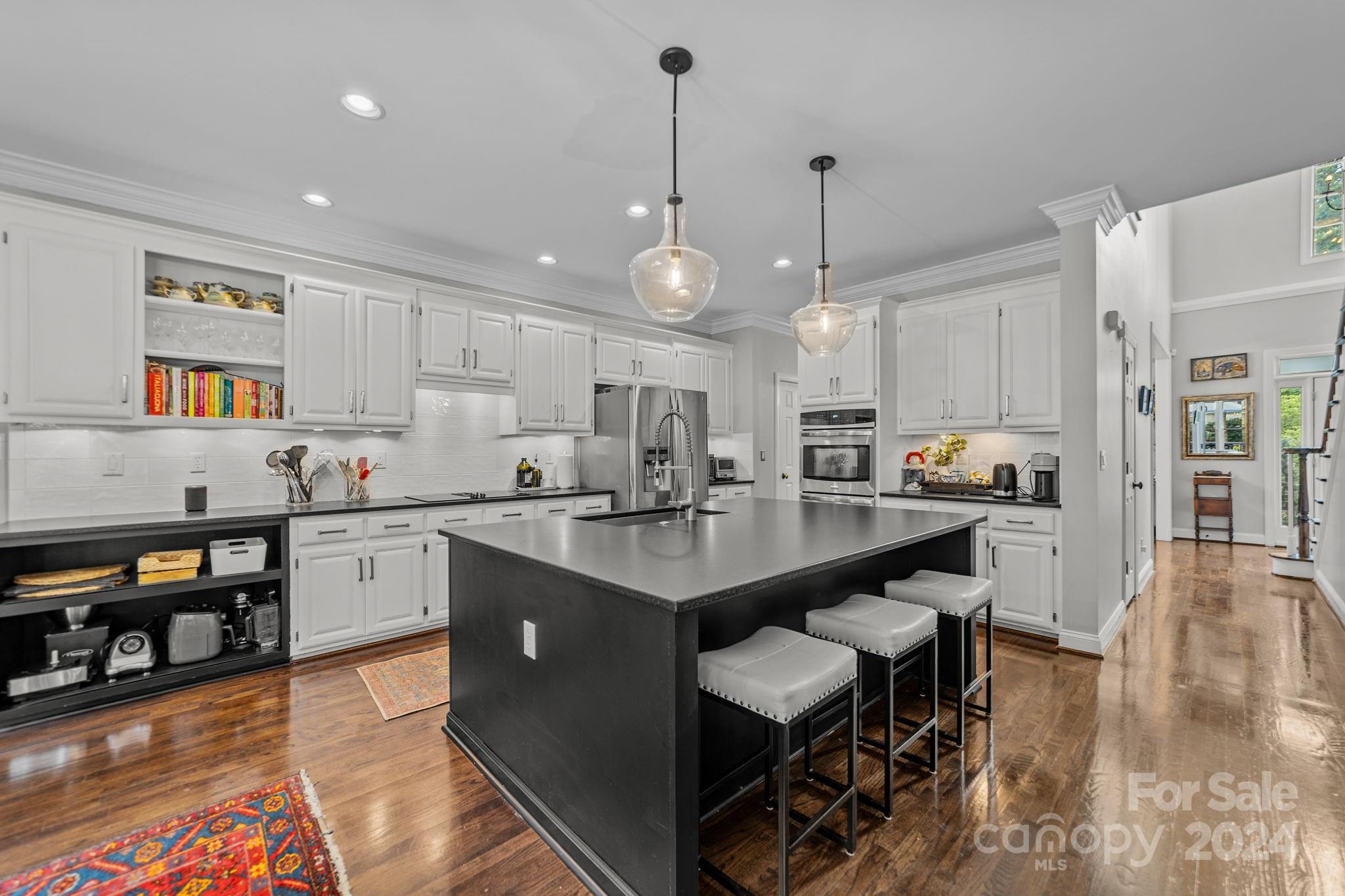 20443 Middletown Road Cornelius, NC 28031 - Photo 13 of 31 a kitchen with stainless steel appliances granite countertop a stove top oven a sink a dining table and chairs with wooden floor