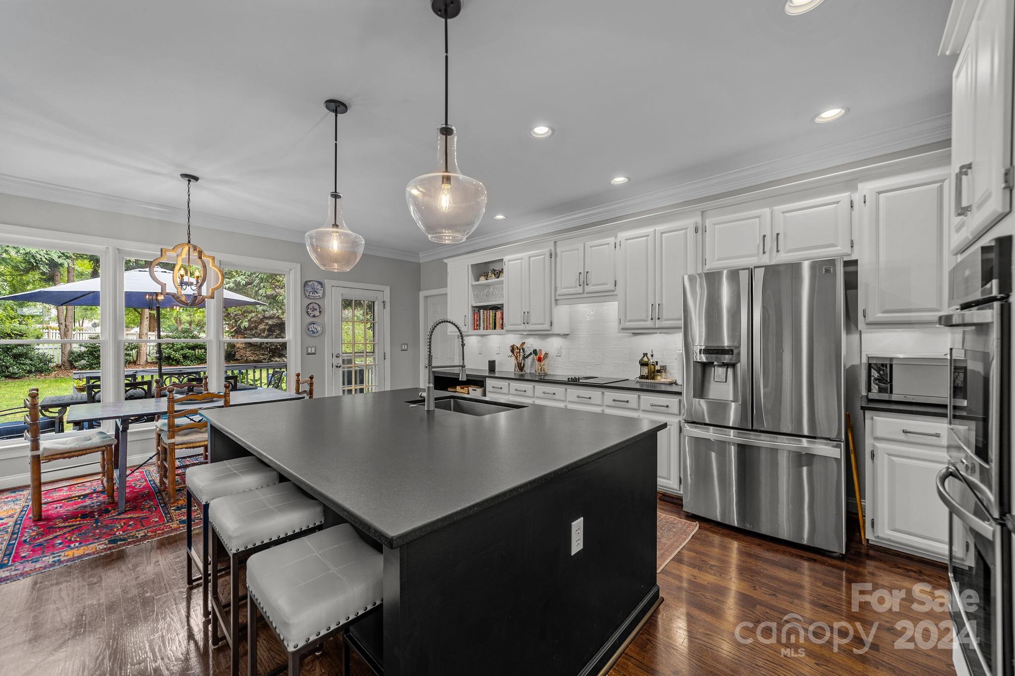 20443 Middletown Road Cornelius, NC 28031 - Photo 15 of 31 a kitchen with kitchen island a large counter top space appliances and a chandelier