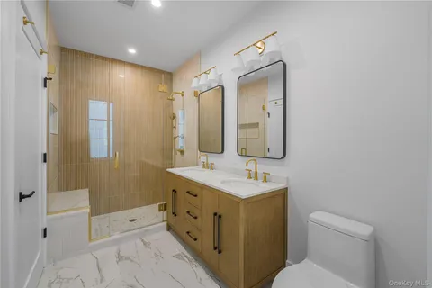 a spacious bathroom with a double vanity sink toilet mirror and shower