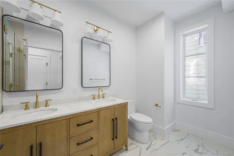 a bathroom with double vanity sink a mirror and a toilet