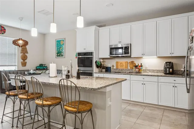 a kitchen with granite countertop kitchen island stainless steel appliances a stove a sink a microwave a refrigerator and cabinets