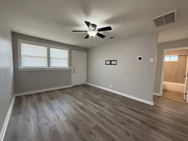 a view of empty room with wooden floor and fan