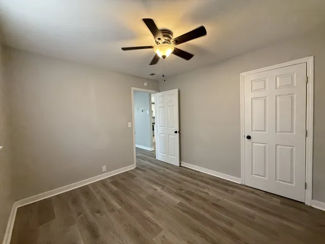 an empty room with wooden floor and ceiling fan