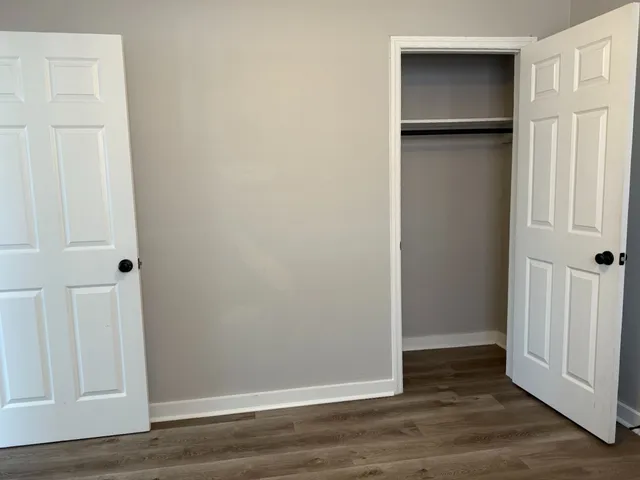 an empty room with wooden floor and closet area