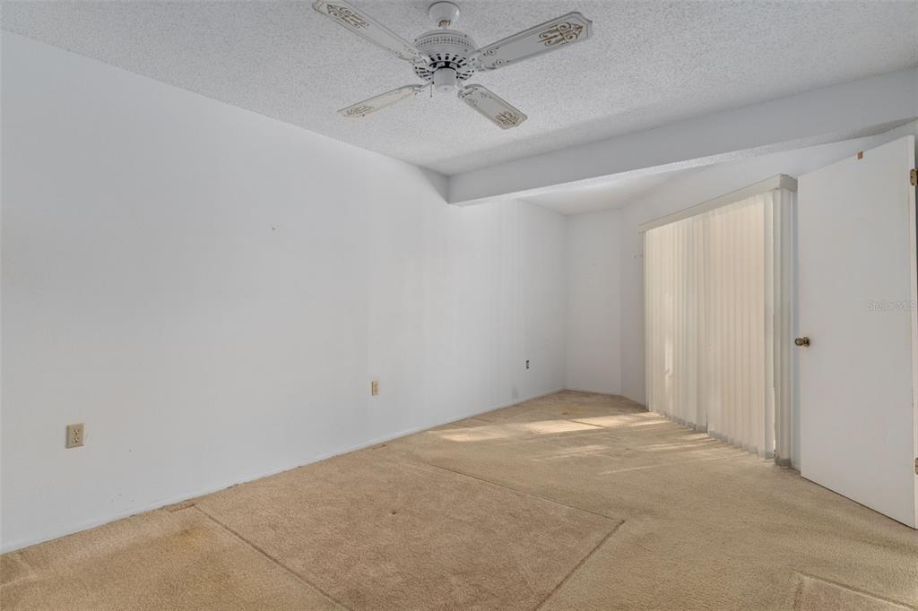 9474 Nakoma Way, Unit E Weeki Wachee, FL 34613 - Photo 17 of 31 an empty room with a ceiling fan and carpet