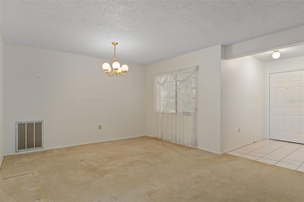 9474 Nakoma Way, Unit E Weeki Wachee, FL 34613 - Photo 9 of 31 a view of an empty room with window and chandelier fan