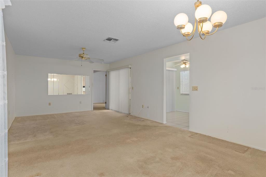 9474 Nakoma Way, Unit E Weeki Wachee, FL 34613 - Photo 10 of 31 an empty room with a chandelier fan and wooden floor