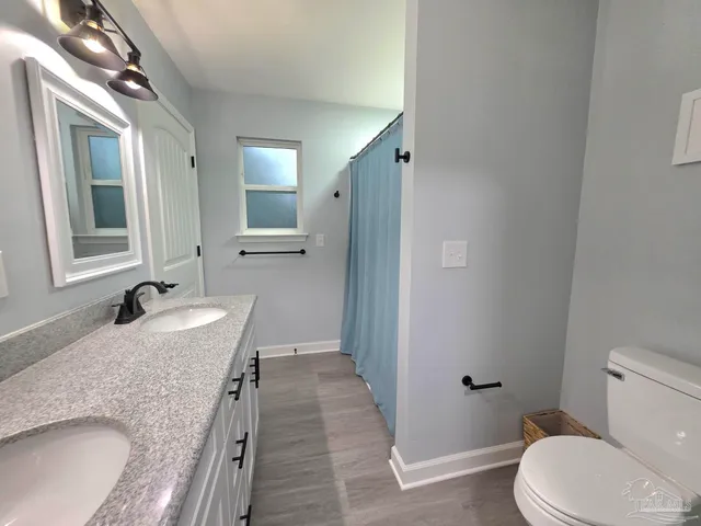 a bathroom with a granite countertop sink and mirror with toilet