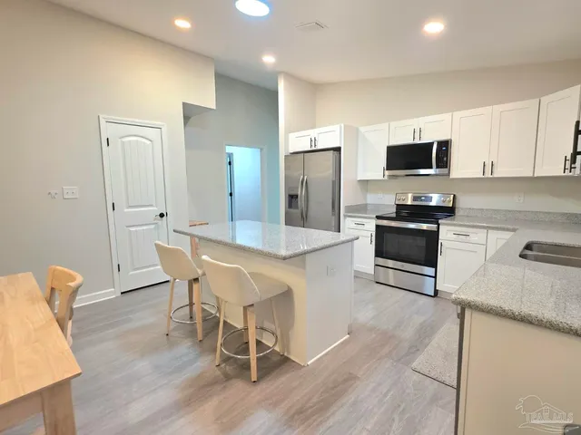 a kitchen with stainless steel appliances granite countertop a stove a sink a refrigerator and a microwave