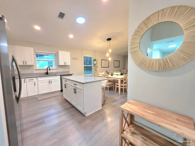 a kitchen with a sink a stove a refrigerator and a dining table with wooden floor