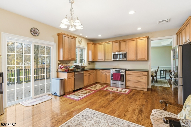3 Marble Lane Randolph, NJ 07869 - Photo 15 of 46 a kitchen with stainless steel appliances granite countertop a stove a refrigerator a sink a dining table and chairs with wooden floor