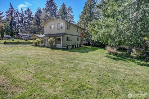 a view of a big house with a big yard and large trees