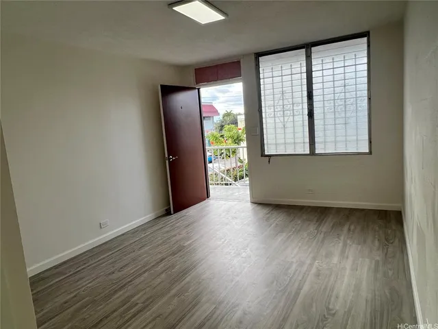 a view of an empty room with wooden floor and a window