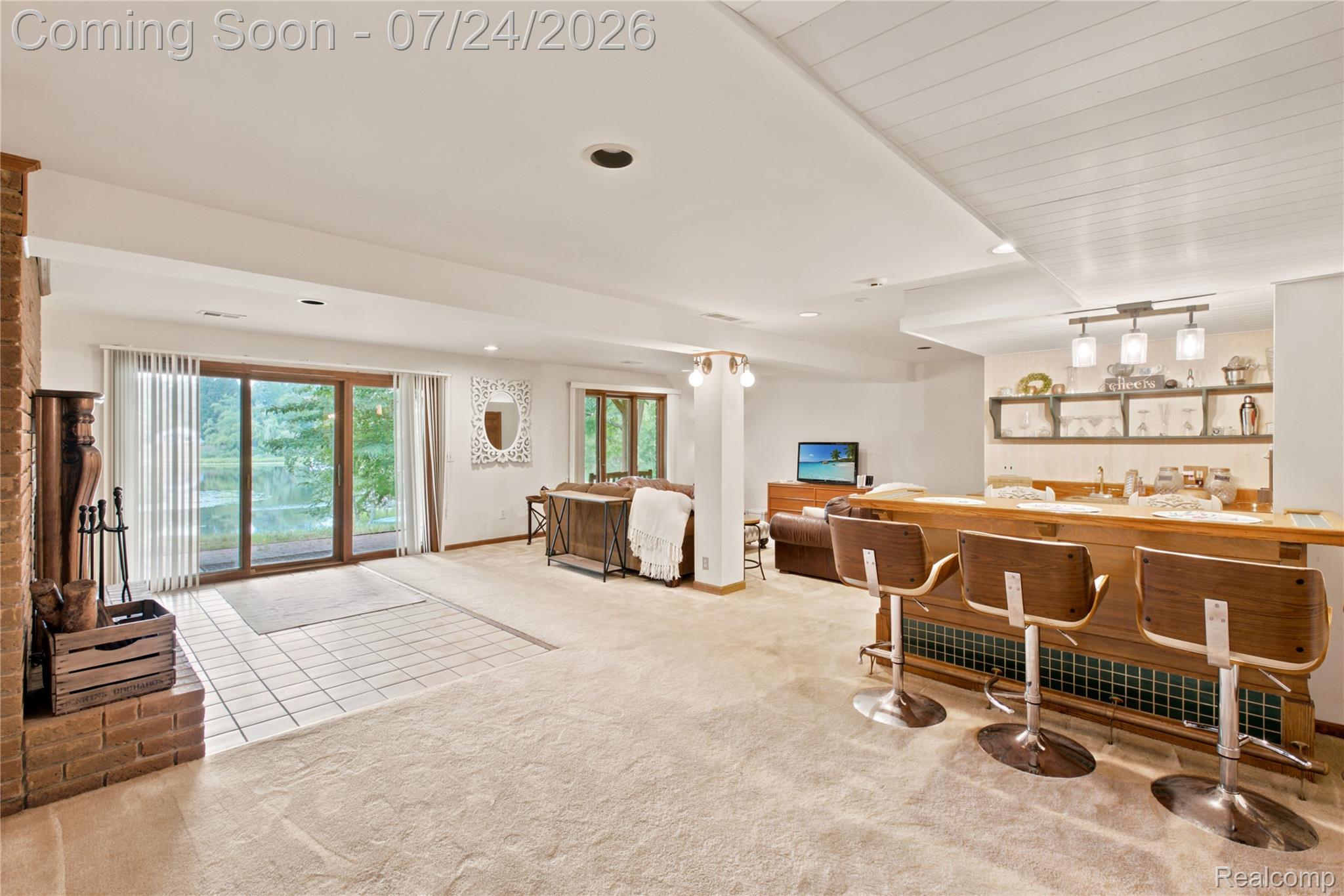 377 Ridgemont Road Oxford, MI 48370 - Photo 34 of 52 Spacious entertainment area featuring a full-service bar with built-in shelving, wood-finish flooring, brick fireplace, and sliding glass doors opening to the exterior