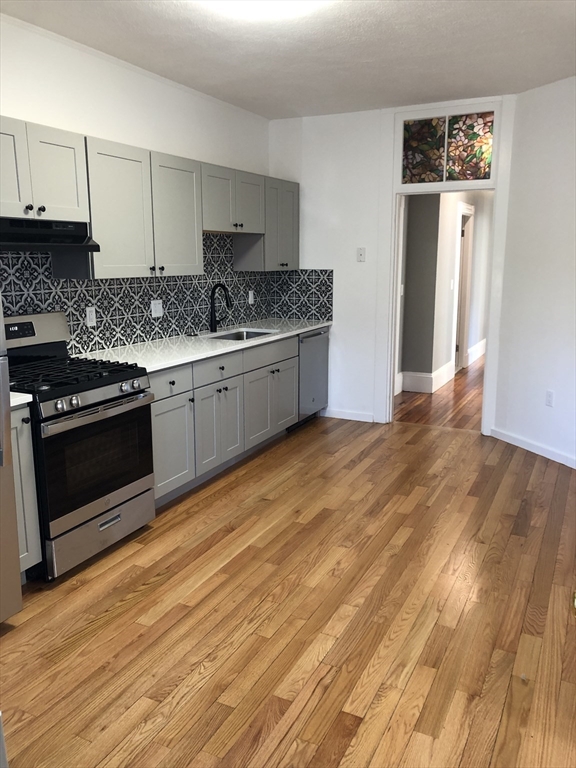 203 High Street Brookline, MA 02445 - Photo 5 of 18 a kitchen with granite countertop a stove a sink and a refrigerator