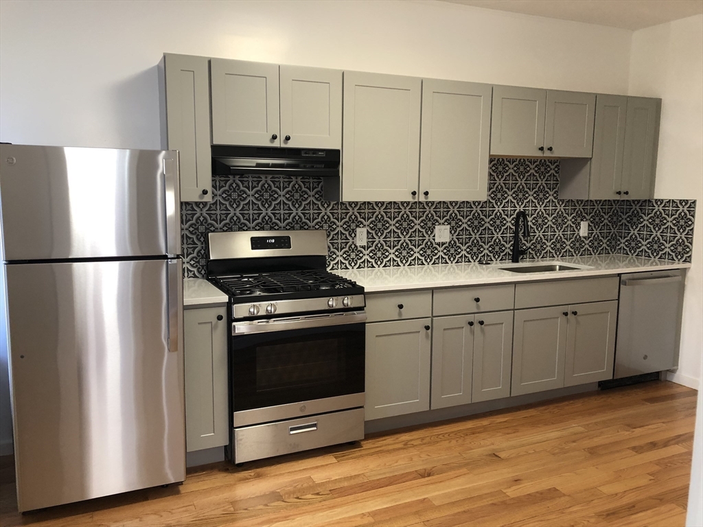 203 High Street Brookline, MA 02445 - Photo 6 of 18 a kitchen with appliances cabinets and wooden floor