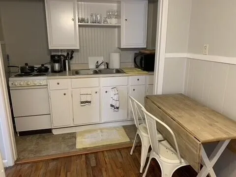 a kitchen with a sink a stove and white cabinets
