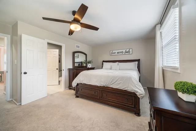 a bedroom with a bed and a potted plant on the dresser