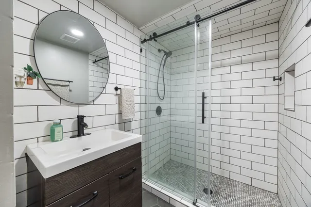 a bathroom with a sink shower and a mirror