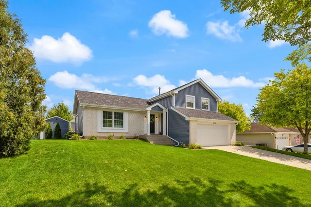 a front view of house with yard and trees in the background