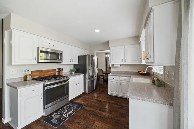 a kitchen with a sink a stove a refrigerator cabinets and a window