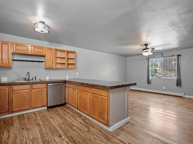 a kitchen with stainless steel appliances granite countertop a sink dishwasher and a stove with wooden floor
