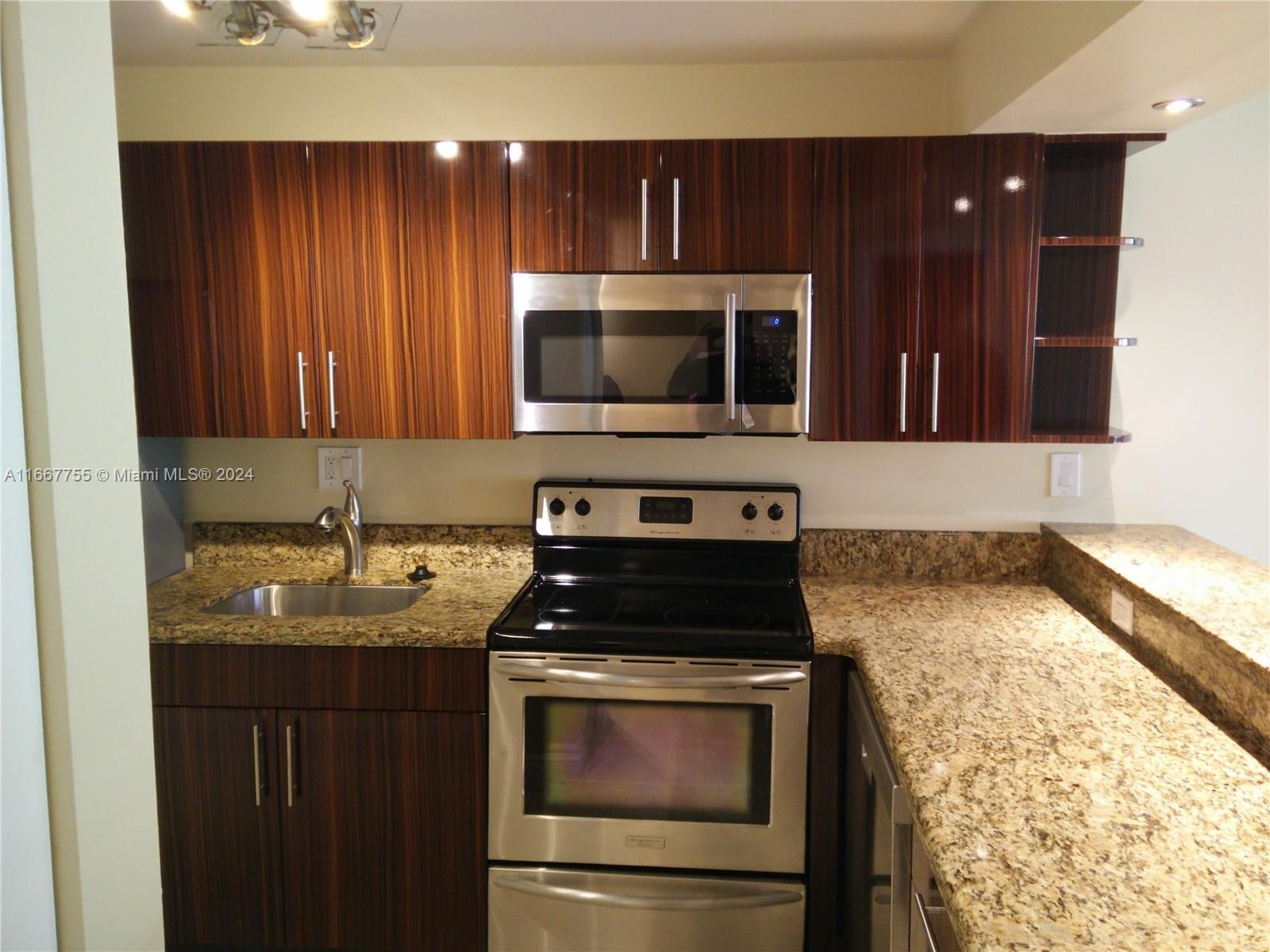 3285 Foxcroft Road, Unit E107 Miramar, FL 33025 - Photo 2 of 9 a kitchen with granite countertop stainless steel appliances a stove sink and microwave