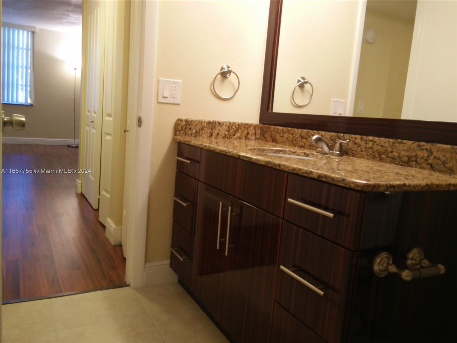 3285 Foxcroft Road, Unit E107 Miramar, FL 33025 - Photo 6 of 9 a bathroom with a granite countertop sink a mirror and shower