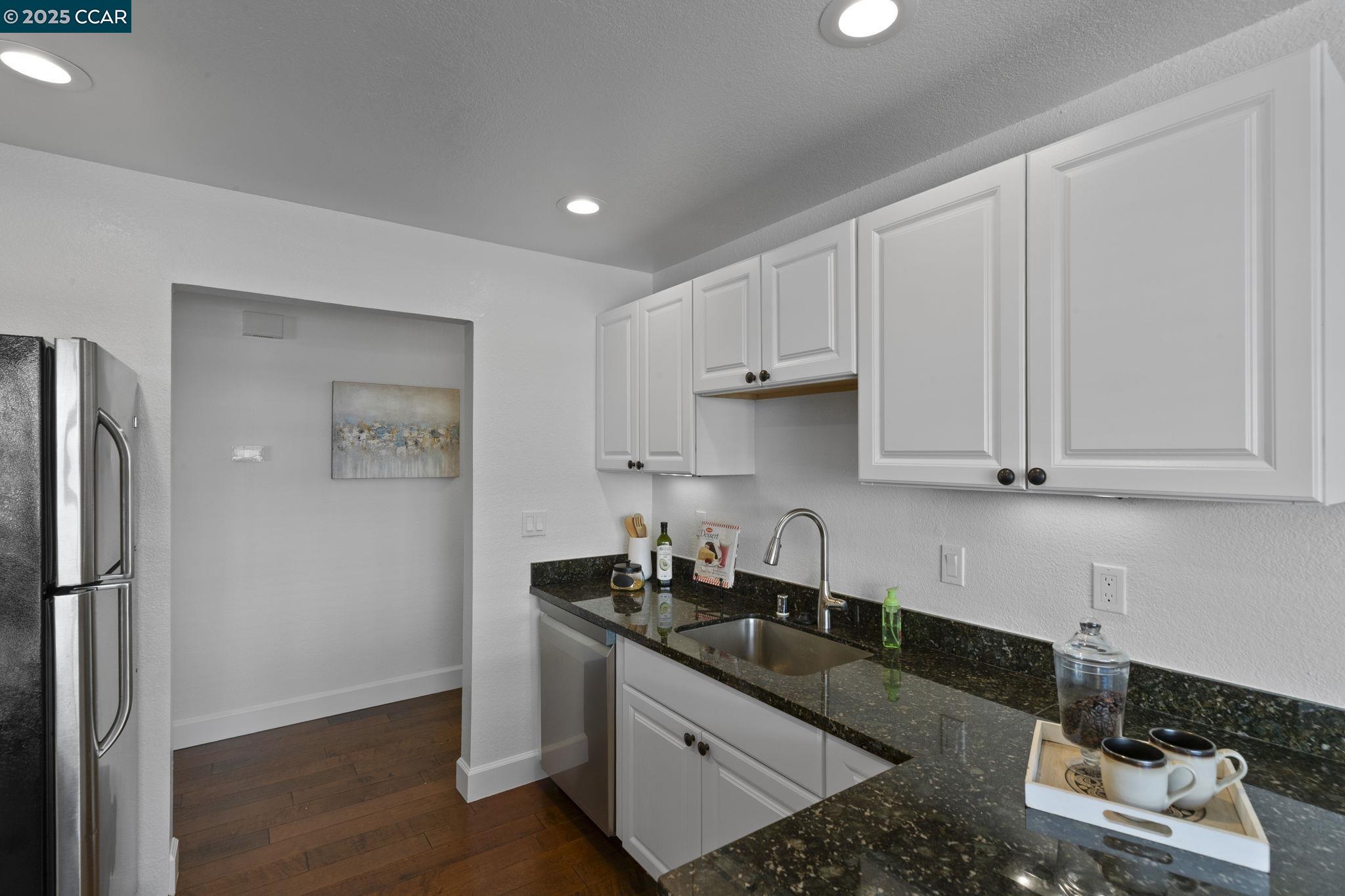 5050 Valley Crest Drive, Unit 63 Concord, CA 94521 - Photo 17 of 55 a kitchen with granite countertop white cabinets and refrigerator