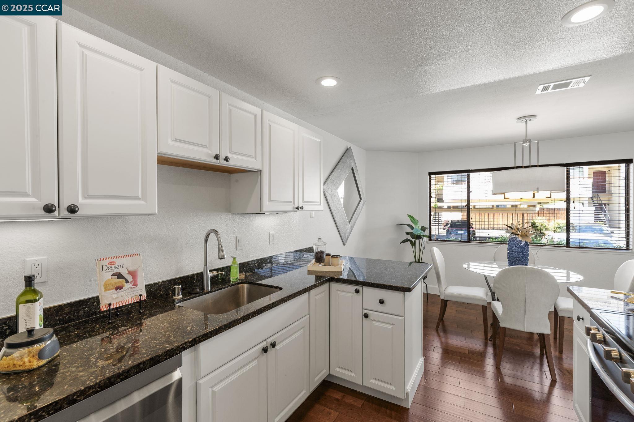 5050 Valley Crest Drive, Unit 63 Concord, CA 94521 - Photo 18 of 55 a kitchen with granite countertop white cabinets a sink a stove and wooden floors