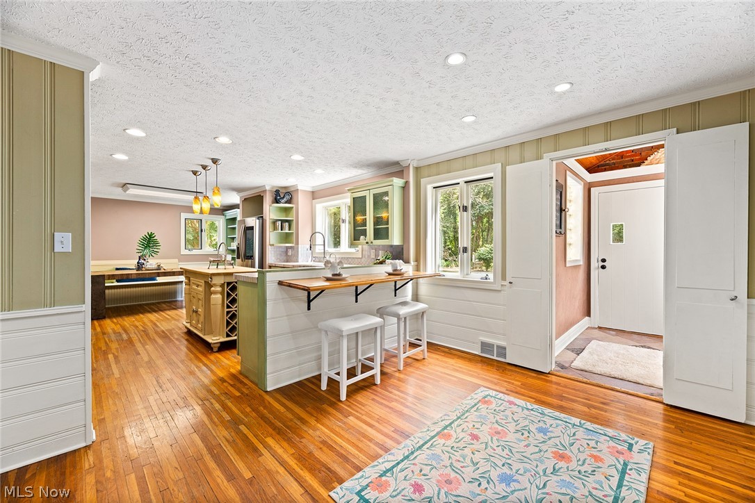 Hardwood flooring throughout, recessed lighting, beadboard wainscoting, and kitchen island with built-in wine storage