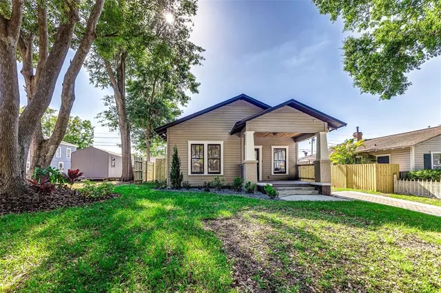 a view of a house with a yard and large trees