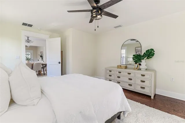 a bedroom with a bed dresser and wooden floor