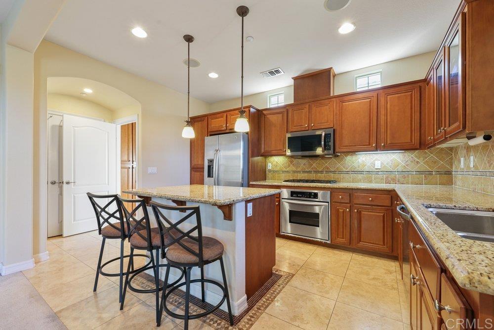 2204 Huntington Point Road, Unit 13 Chula Vista, CA 91914 - Photo 24 of 28 a kitchen with stainless steel appliances granite countertop a stove top oven a sink dishwasher a dining table and chairs with wooden floor