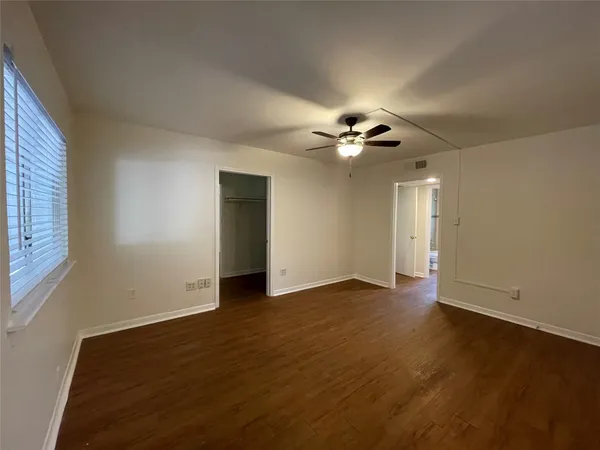 a view of an empty room with a ceiling fan and window