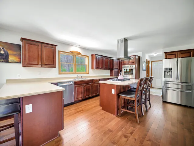 a kitchen with stainless steel appliances granite countertop a table chairs sink and cabinets