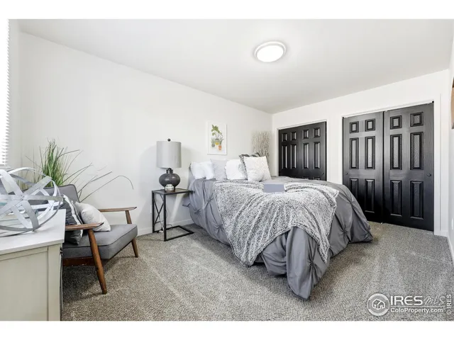 a spacious bedroom with a bed a couch and potted plant on the dresser