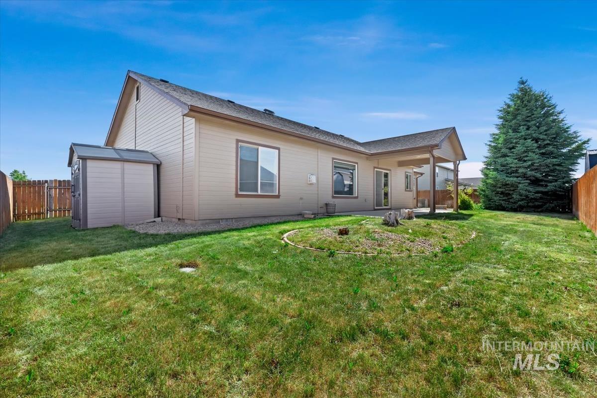 640 Southwest Miner Street Mountain Home, ID 83647 - Photo 9 of 35 Expansive backyard featuring a covered patio, mature evergreen tree, and a garden shed