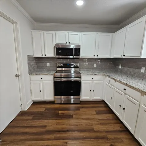 a kitchen with stainless steel appliances granite countertop a stove a sink and white cabinets