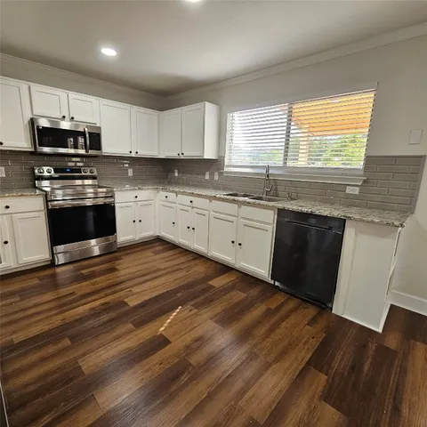 a large kitchen with granite countertop a stove top oven a sink dishwasher a dining table and chairs with wooden floor