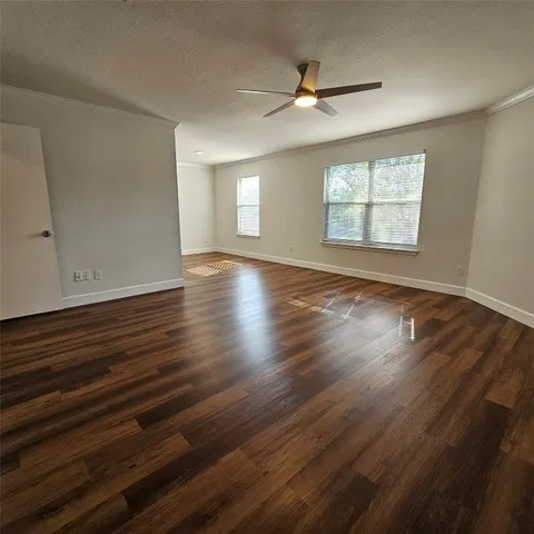 an empty room with wooden floor window and ceiling fan