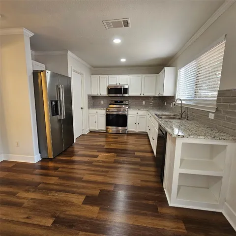 a kitchen with granite countertop a refrigerator and a stove top oven