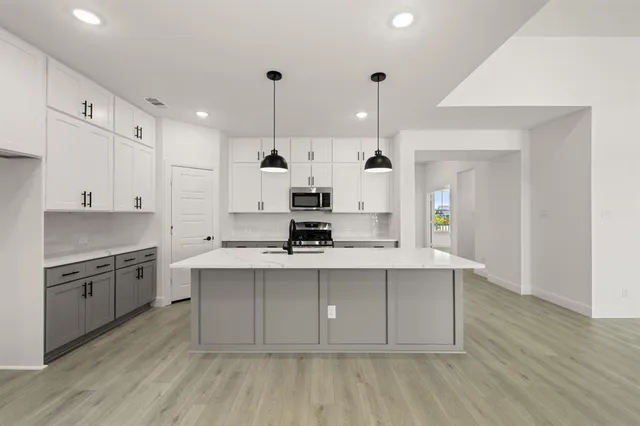 a large kitchen with stainless steel appliances a sink a stove and a refrigerator