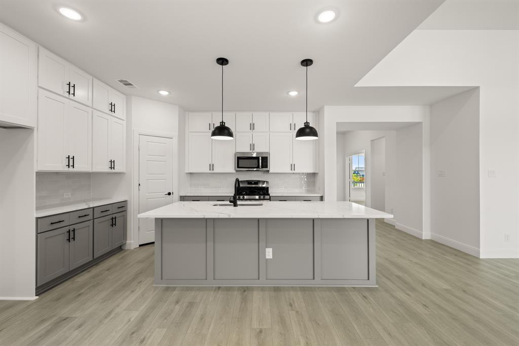 408 Dylan Way Midlothian, TX 76065 - Photo 28 of 40 a kitchen with kitchen island a sink a stove and a refrigerator