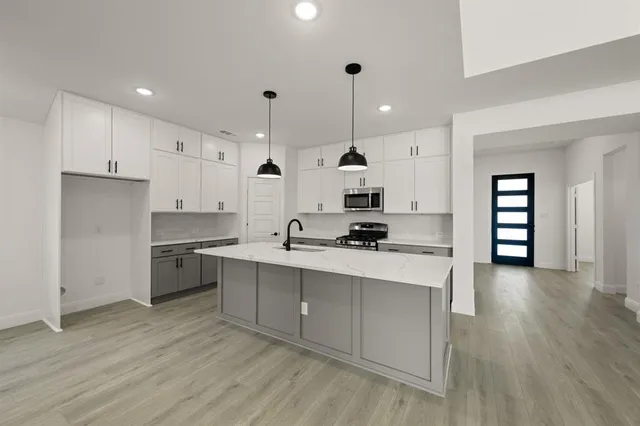 a kitchen with stainless steel appliances granite countertop a sink a stove and a refrigerator