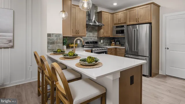 a kitchen with stainless steel appliances granite countertop a stove a refrigerator a sink dishwasher a dining table and chairs with wooden floor